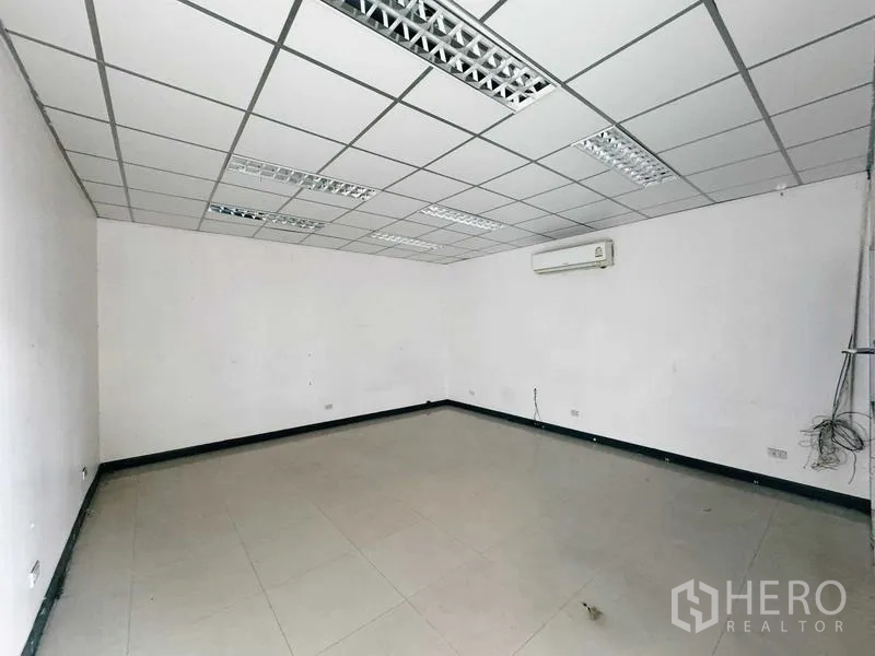 Warehouse for rent in Din Daeng, Bangkok - Front office area with glass partition and fluorescent lighting.