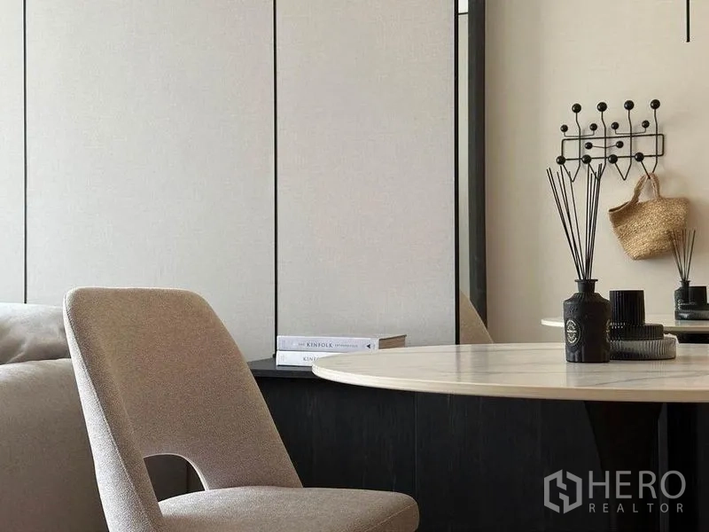 Condominium for rent in Watthana, Bangkok - Detail of dining area with beige chair, round table, reed diffuser decor and wall hooks.