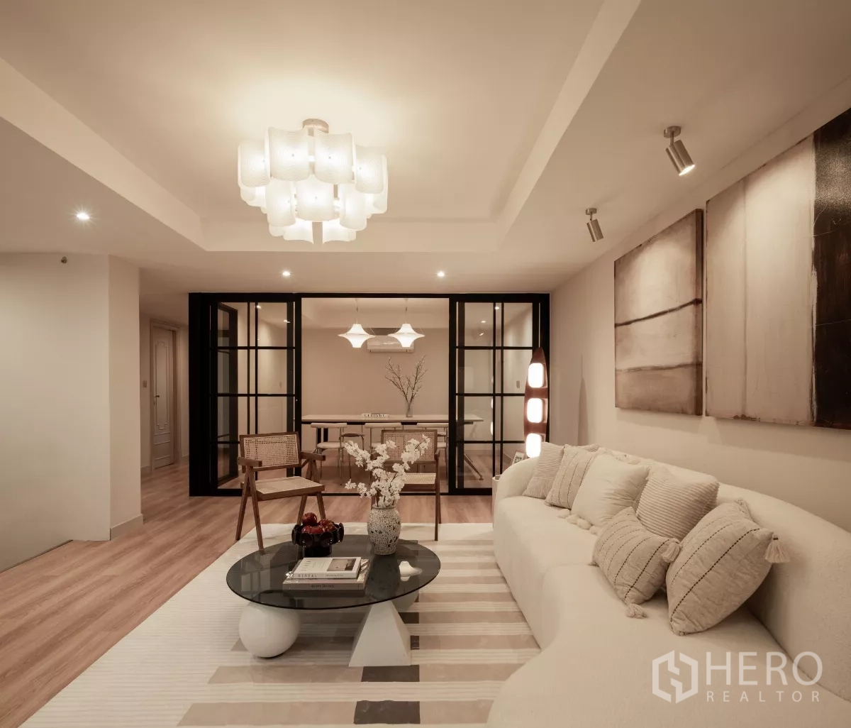 带办公室的家 出售在Phra Khanong, Bangkok - 温馨客厅，弧形沙发、玻璃隔断与现代灯光。