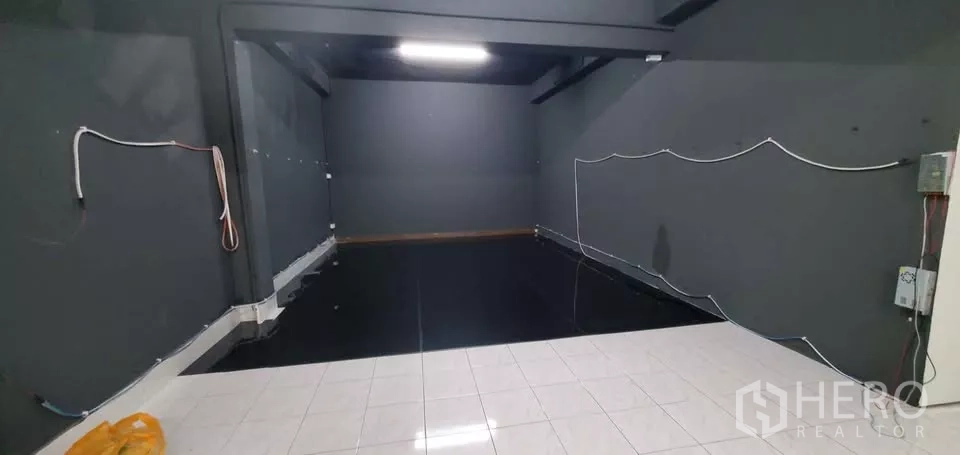 Office Space for rent in Suan Luang, Bangkok - Another angle of the dark gray studio-style room with black floor and white tile transition area.