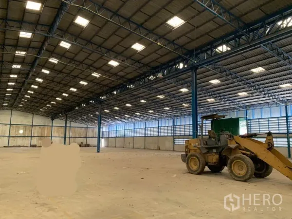 โรงงาน ให้เช่าในChon Buri - พื้นการผลิตโล่ง เสาโครงสีฟ้า พร้อมรถตักบนพื้นคอนกรีต