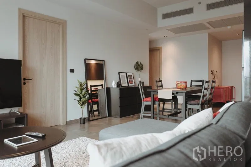 Condominium for rent in Watthana, Bangkok - Spacious lounge facing the dining table and TV, with light wood doors and décor.