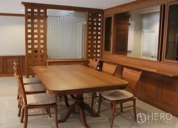 Condominium for rent in Watthana, Bangkok - Dining area with six-seat wooden table, lattice partition and built-in cabinetry.