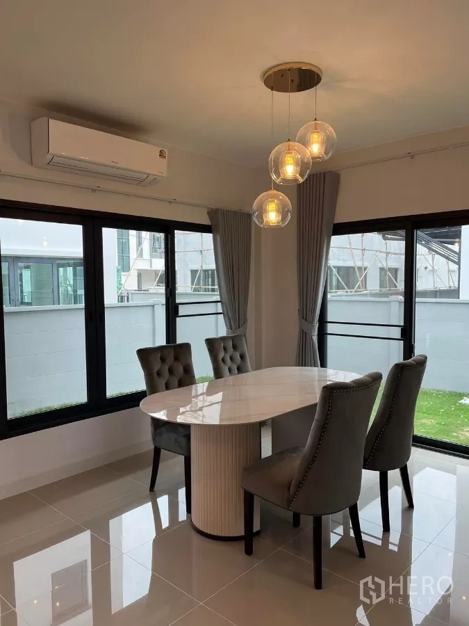 Detached House for rent or sale in Bang Phli, Samut Prakan - Corner dining area with a marble-top table, four upholstered chairs, and pendant lights by windows.