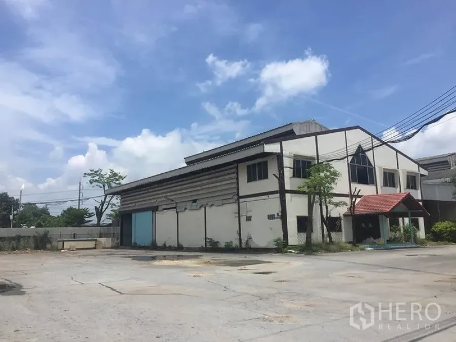 Office Space for rent in Sai Noi, Nonthaburi - Two-storey industrial office building with blue sliding doors and ample open parking area.