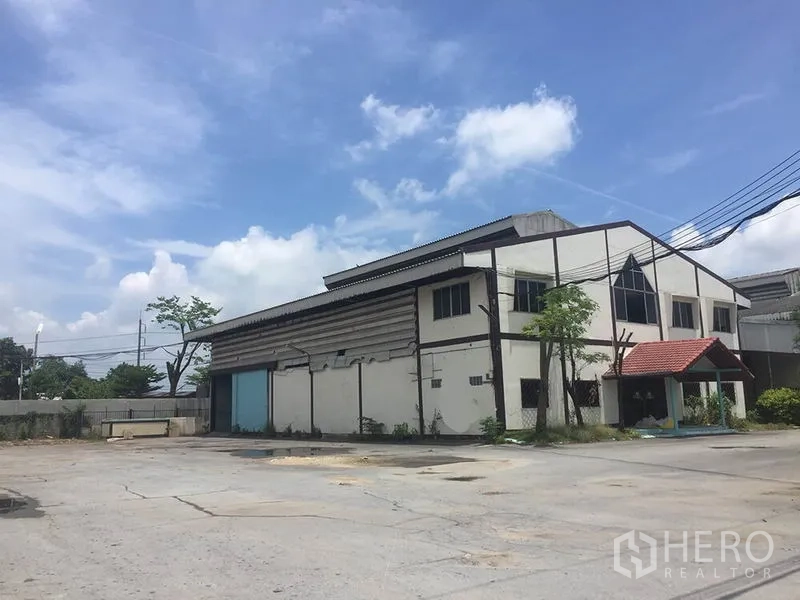 Office Space for rent in Sai Noi, Nonthaburi - Two-storey industrial office building with blue sliding doors and ample open parking area.