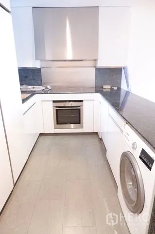 公寓 出售在Sathon, Bangkok - 现代U型厨房，石质台面，配烤箱、炉灶与洗衣机。