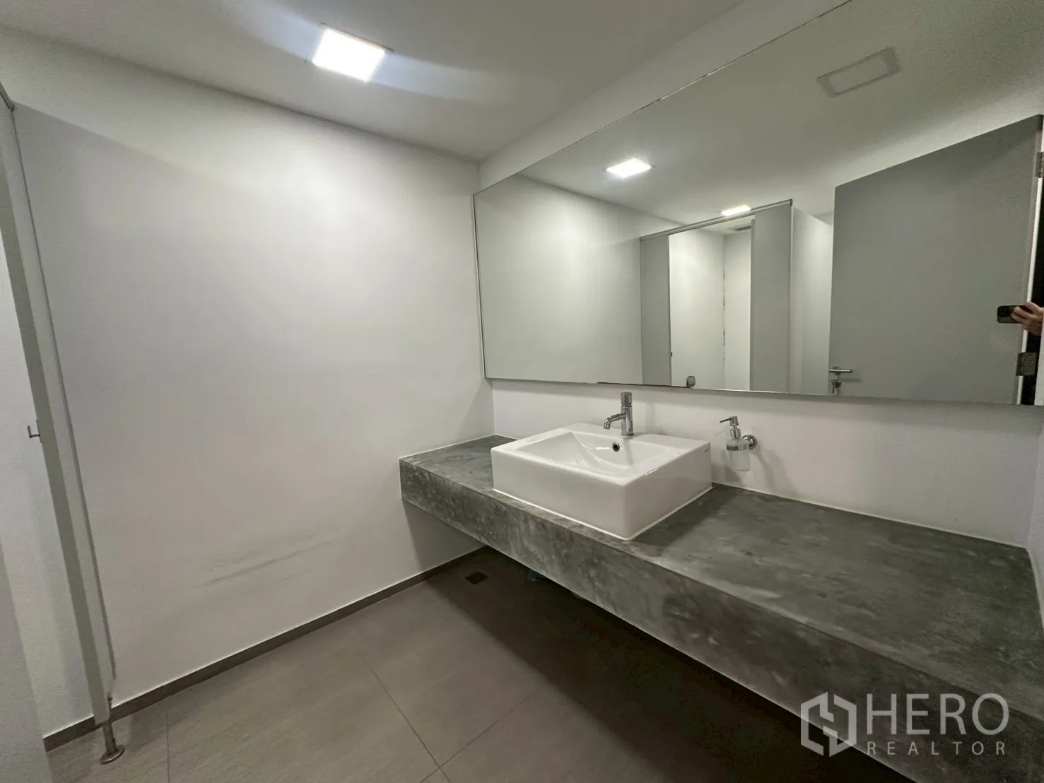 Office Space for rent - Restroom with long concrete countertop, square basin and wide mirror.