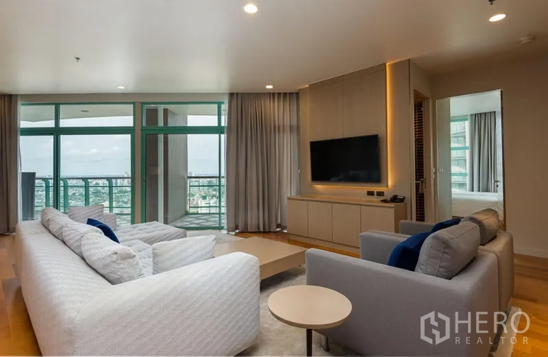 คอนโด ให้เช่าในBang Kho Laem, Bangkok - ห้องนั่งเล่นพร้อมโซฟา ผนังทีวี และประตูระเบียงเปิดสู่วิวแม่น้ำและสกายไลน์