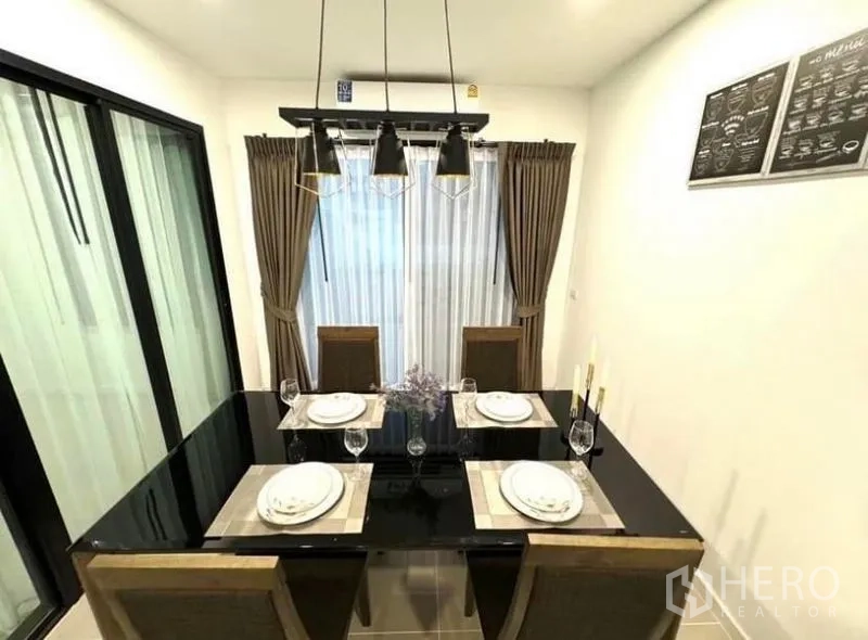 Townhouse for rent - Dining area set for four with black glass table, pendant lights, and curtains.