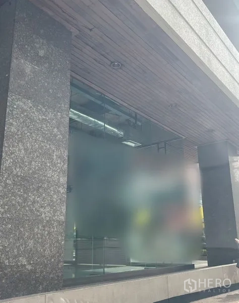 零售空间 出租 - 石柱与木质吊顶下的玻璃店面特写。