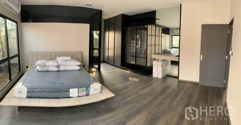 Townhouse for rent in Bang Phli, Samut Prakan - Expansive master bedroom with floor-to-ceiling windows and glass-front wardrobe.