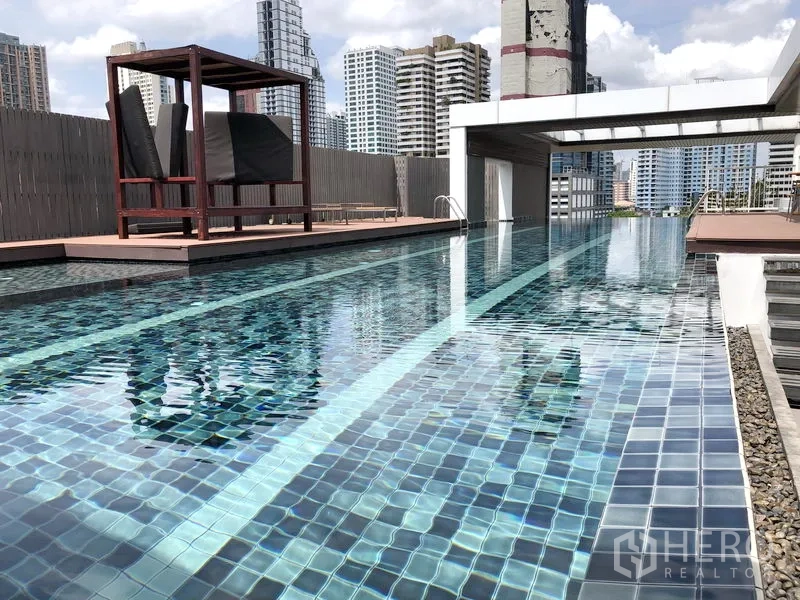 Condominium for rent in Watthana, Bangkok - Rooftop swimming pool with city skyline views and shaded seating deck.
