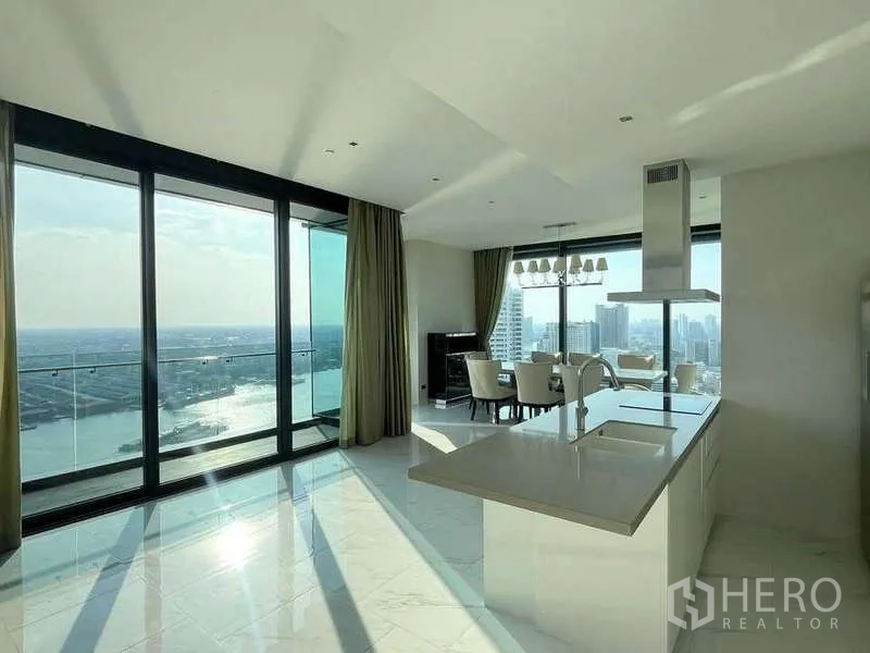 Condominium for rent or sale in Bangkok - Open-plan living, dining and island kitchen with expansive river-facing windows.
