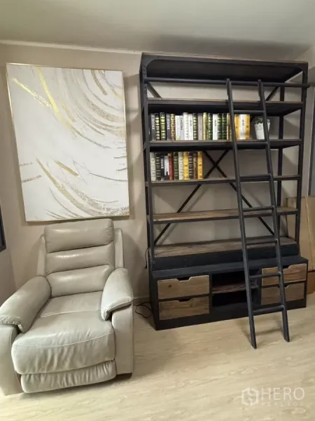Condominium for rent in Phra Khanong, Bangkok - Cozy reading corner with recliner and tall industrial bookshelf with ladder.