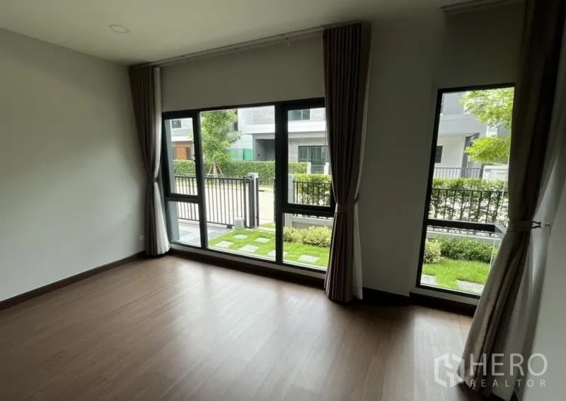 独立式住宅 出租在Bang Phli, Samut Prakan - 一层房间，落地窗面向花园与前院大门。