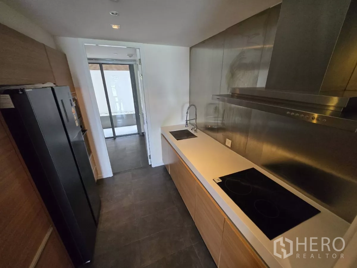 公寓 出租在Yan Nawa, Bangkok - 厨房另一视角，双水槽与不锈钢防溅板，通向生活阳台。