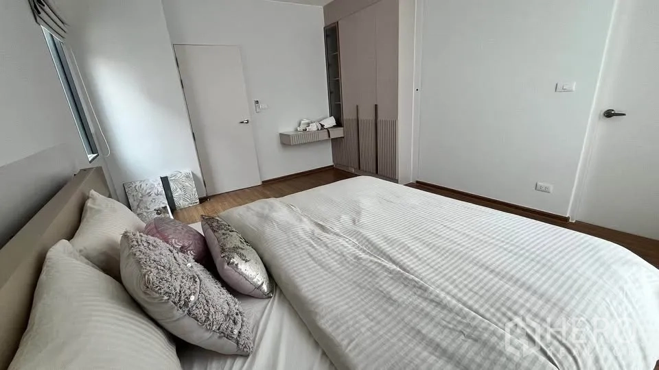 Townhouse for rent or sale in Bang Phli, Samut Prakan - Cozy bedroom view across bed toward wardrobe and shelf.