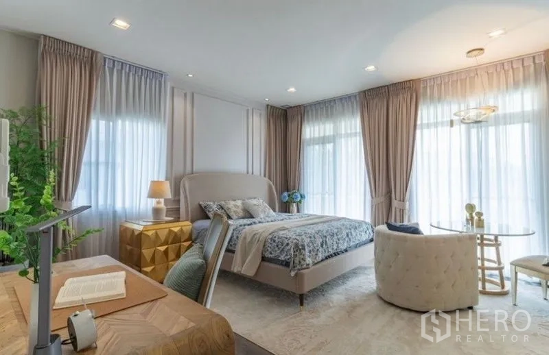 Detached House for rent in Bang Phli, Samut Prakan - Spacious primary bedroom with seating nook, desk and full-height curtains.