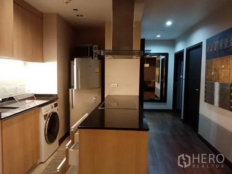 公寓 出租在Sathon, Bangkok - 一体化厨房，黑色花岗岩台面，电磁炉、烟机、冰箱与洗烘一体机。