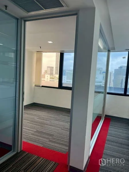 Office Space for rent - Bright corridor leading to a glass-partitioned private office with windows.