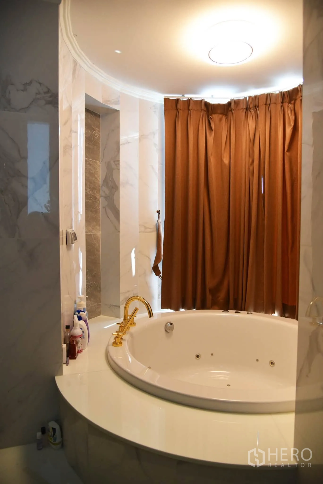 Condominium for sale in Khlong San, Bangkok - Bathroom featuring a round whirlpool tub, marble walls, and a gold faucet.