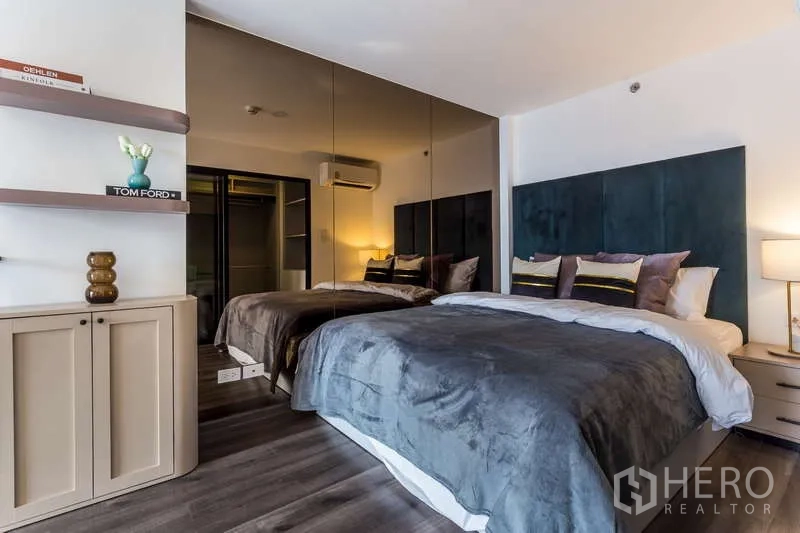 Condominium for rent or sale - Bedroom with upholstered headboard, mirrored wardrobe and warm lighting.