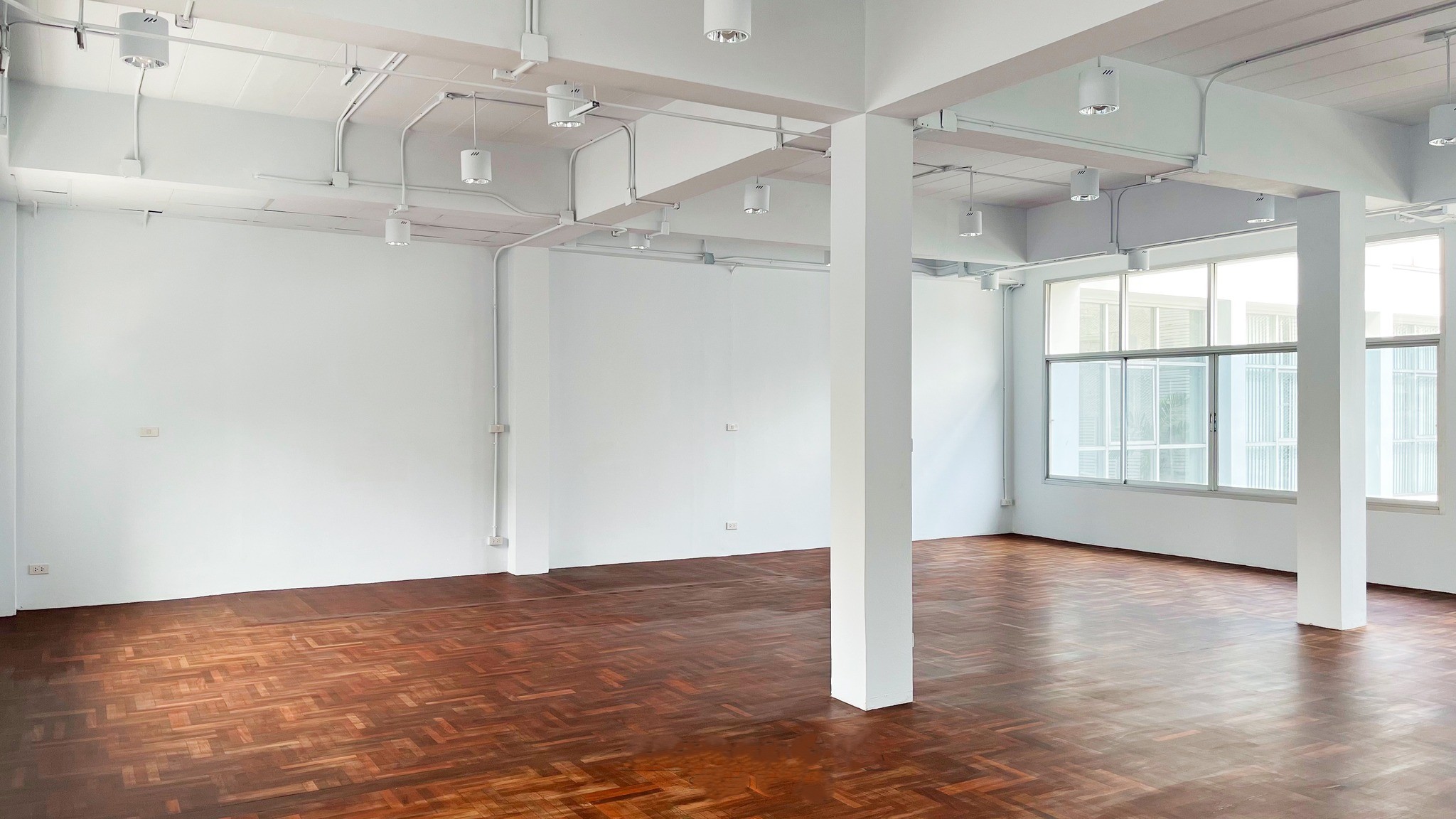 零售空间 出租在Watthana, Bangkok - 开放式零售室内，拼花木地板，白色柱体，大窗与天花射灯。
