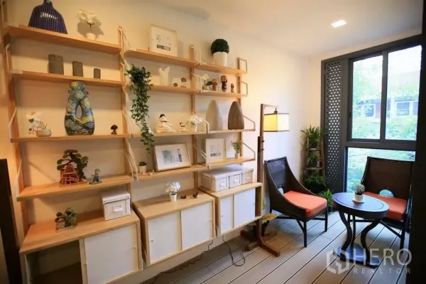 Condominium for rent in Watthana, Bangkok - Wall-to-wall wooden shelving with two chairs and a round table beside a garden-view window.