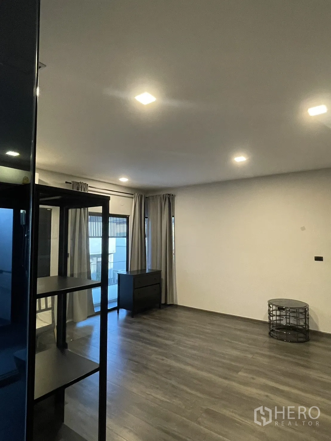Townhouse for sale in Bang Phli, Samut Prakan - Spacious upper room with balcony doors, curtains, and dark wood flooring.