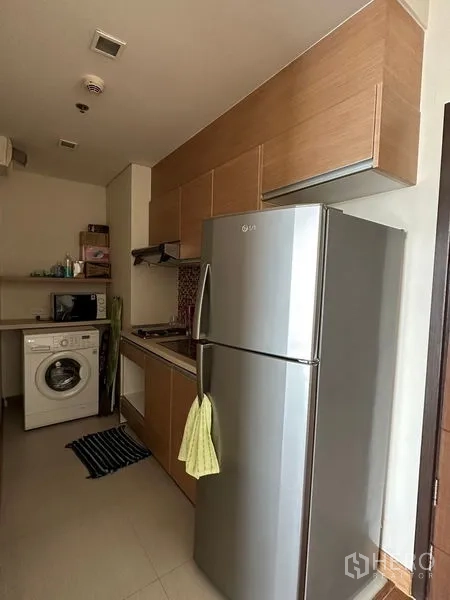 Condominium for sale in Watthana, Bangkok - Compact kitchen with wooden cabinets, stainless refrigerator and washing machine.