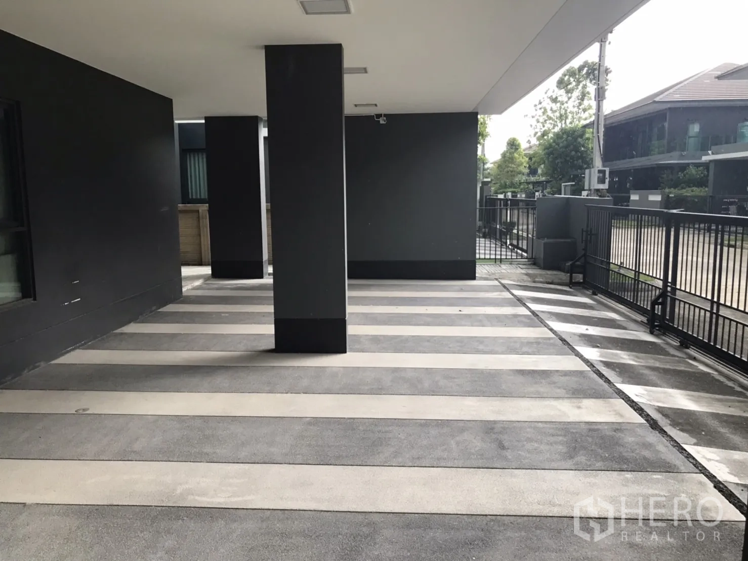 Detached House for rent in Bang Kapi, Bangkok - Covered carport with striped concrete floor and secure gate for multiple cars.