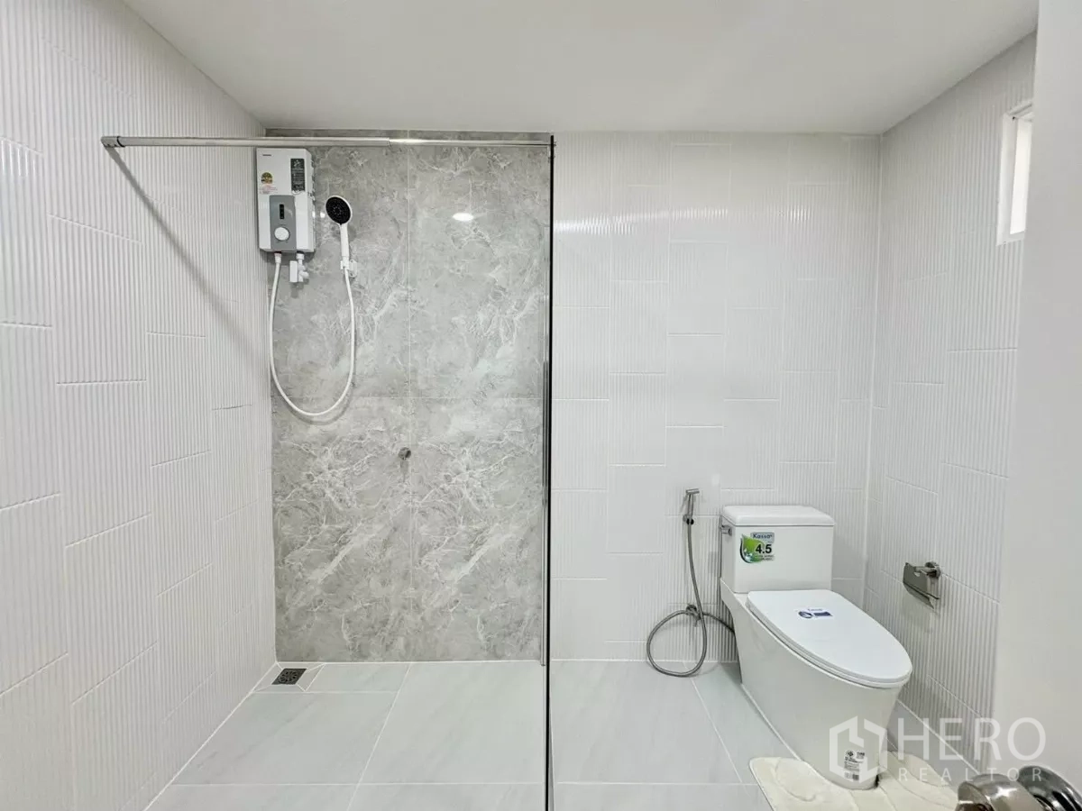 Detached House for rent in Huai Khwang, Bangkok - Bathroom with shower zone and toilet set against white tiles