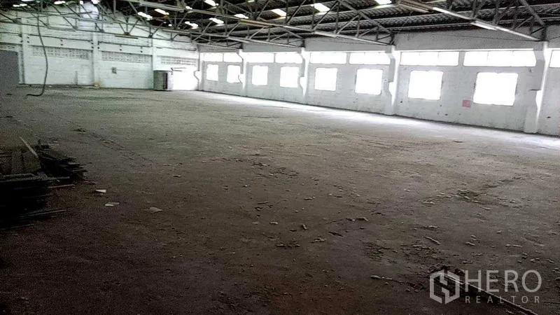 Warehouse for rent in Nakhon Pathom - Large clear-span storage space with rows of windows and a roller door at the end.
