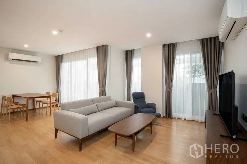 Condominium for rent in Phra Khanong, Bangkok - Open-plan living and dining room with large windows, recliner and flat-screen TV near BTS Thonglor.