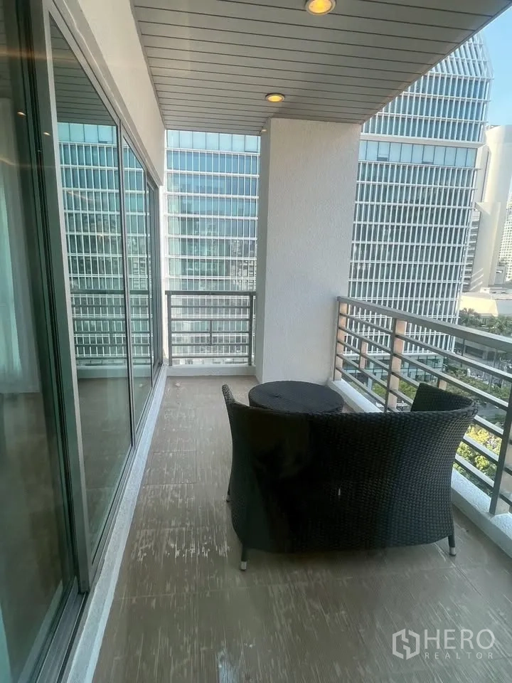 คอนโด for rent in Pathum Wan, Bangkok - ระเบียงกว้างพร้อมเก้าอี้หวายและโต๊ะ ชมวิวตึกสูง มีประตูกระจกบานเลื่อนและไฟดาวน์ไลท์เพดาน