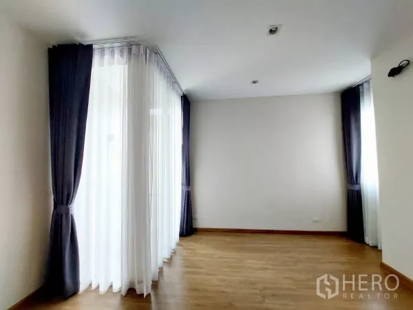 ทาวน์เฮาส์ ให้เช่าในLat Phrao, Bangkok - ห้องนอนมุมสว่าง พื้นไม้ พร้อมหน้าต่างเต็มผนังและม่านทึบ-โปร่ง