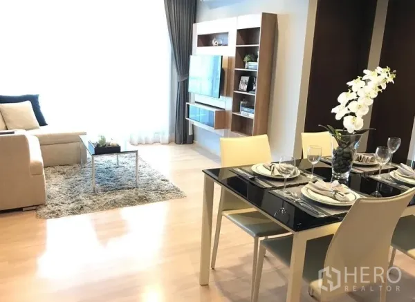 Condominium for rent in Sathon, Bangkok - Bright open-plan living and dining area with sofa, rug, glass-top table and built-in TV wall in a Sathon condo.