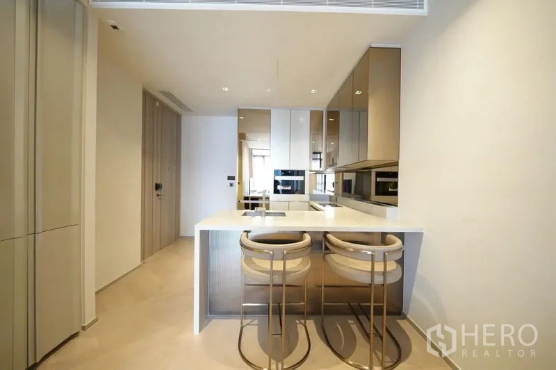 Condominium for rent - Contemporary kitchen with white island breakfast bar, mirrored cabinetry and integrated appliances.