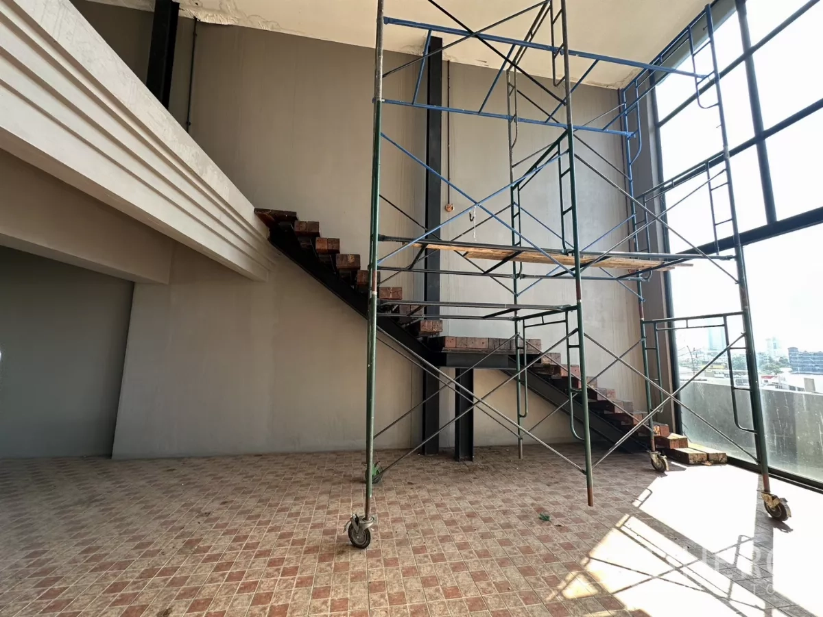 店屋 出租在Bang Na, Bangkok - 高挑空间，夹层楼梯与落地窗旁的脚手架。