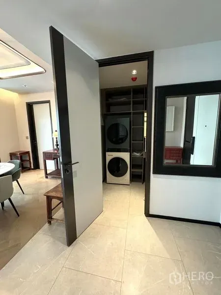 Condominium for rent in Watthana, Bangkok - Utility room with open shelving and stacked washer–dryer beside dining area.