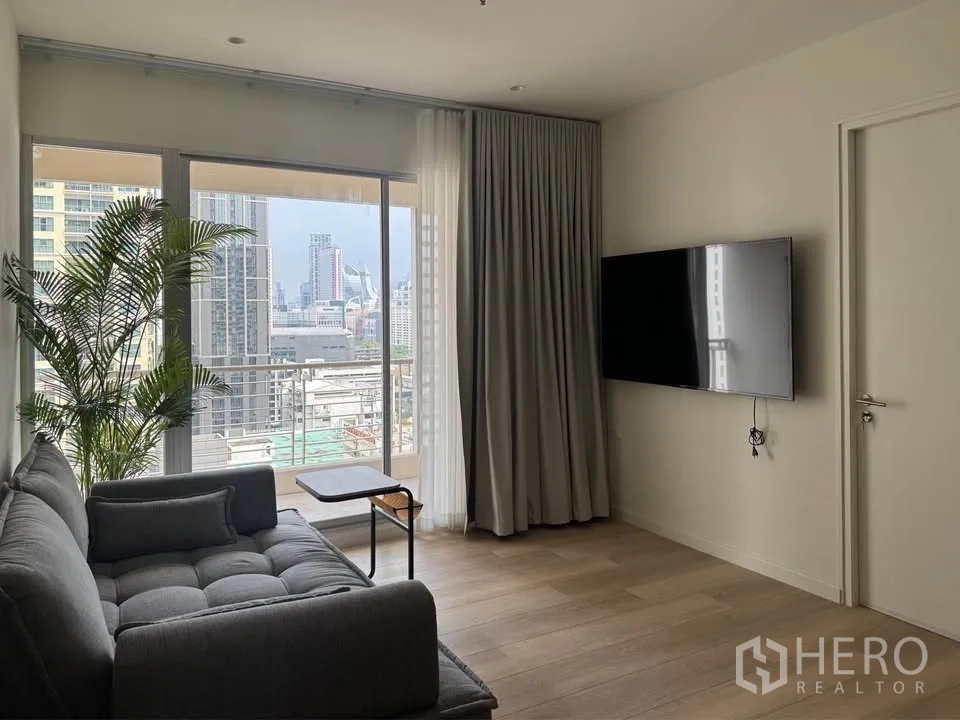 คอนโด for rent in Ratchathewi, Bangkok - ห้องนั่งเล่นสว่าง โซฟา ทีวีติดผนัง กระจกเต็มบานและระเบียงวิวเมือง