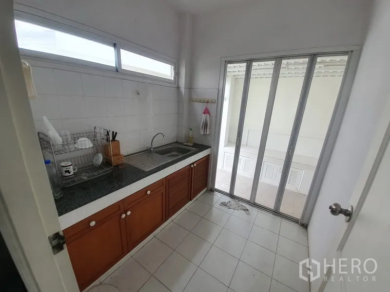 บ้าน ให้เช่าในLat Krabang, Bangkok - ครัวไทยแยกเป็นสัดส่วน ซิงก์คู่ ผนังกระเบื้อง และประตูกระจกบานเลื่อนออกลานซักล้าง.