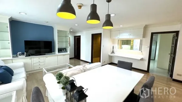 คอนโด ให้เช่าหรือขายในWatthana, Bangkok - พื้นที่นั่งเล่นและรับประทานอาหารแบบโอเพนพร้อมโซฟาสีขาว ผนังทีวี และโคมไฟแขวนโทนดำ