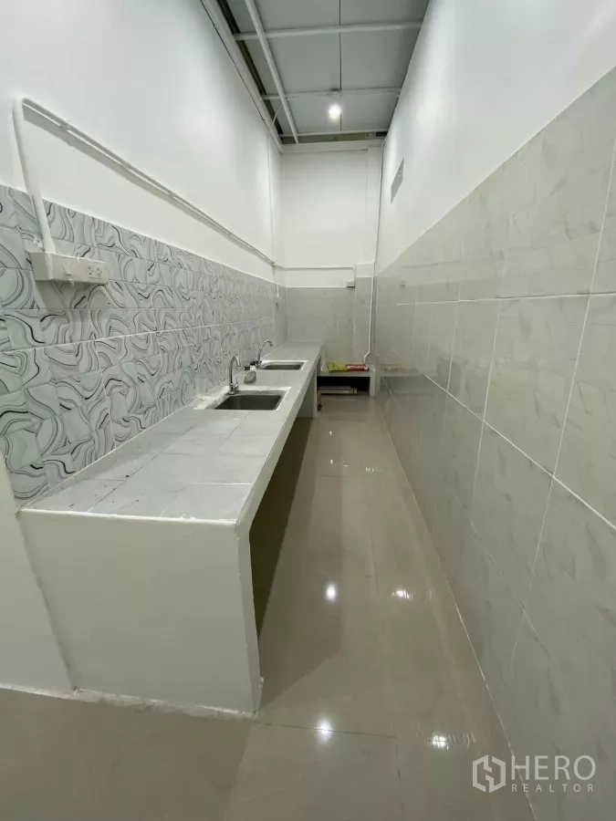 Detached House for rent in Bang Na, Bangkok - Narrow Thai-style wet kitchen with tiled countertops, dual stainless sinks and high ceiling.
