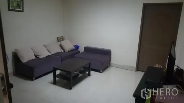 Shophouse for sale in Khlong Toei, Bangkok - Cozy living room with L-shaped sofa, coffee table and TV stand on tiled flooring.