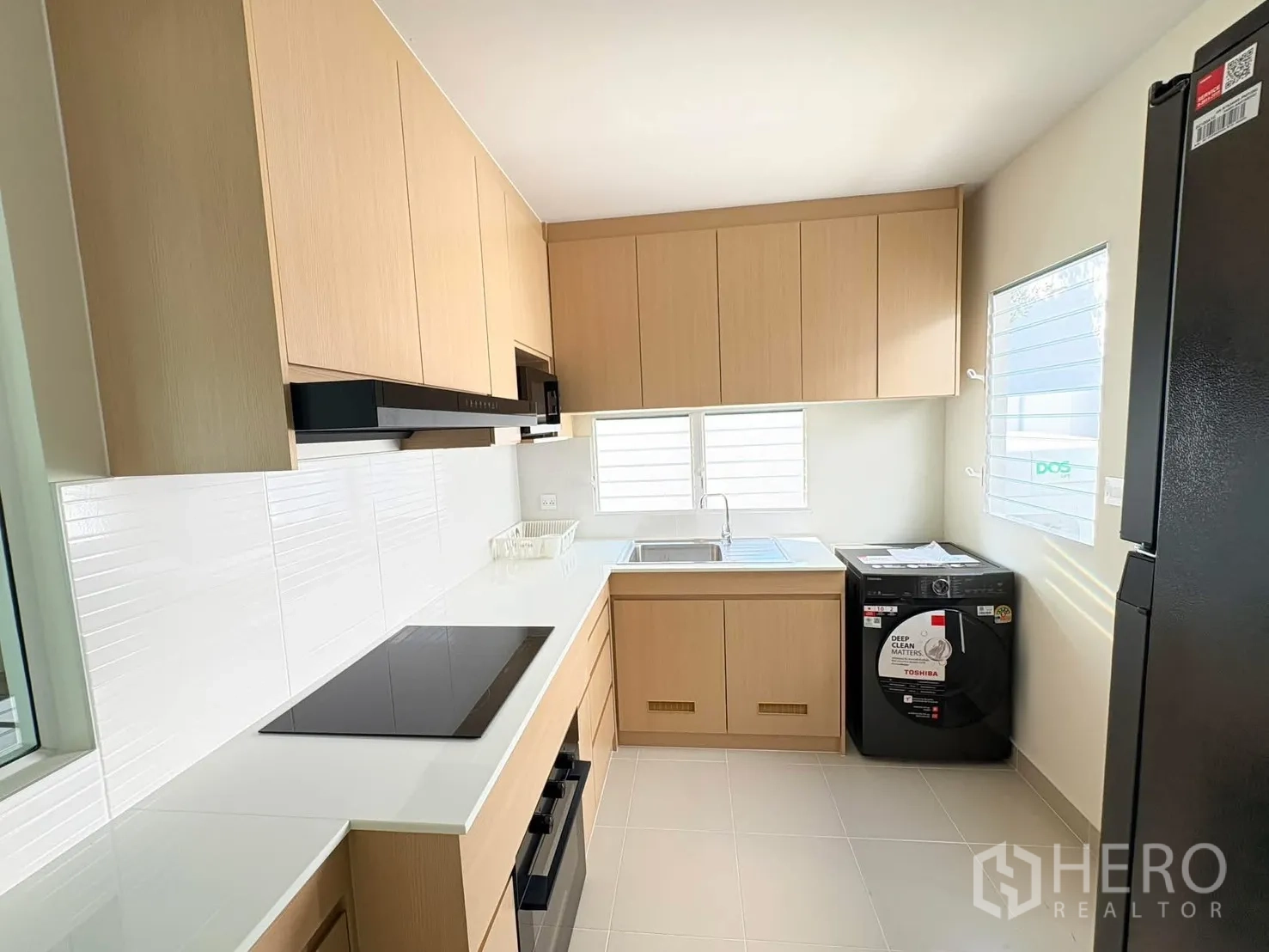 独立式住宅 for rent in Bang Phli, Samut Prakan - 现代U形厨房，浅木柜体，电磁炉、烤箱、水槽与洗衣机齐全。