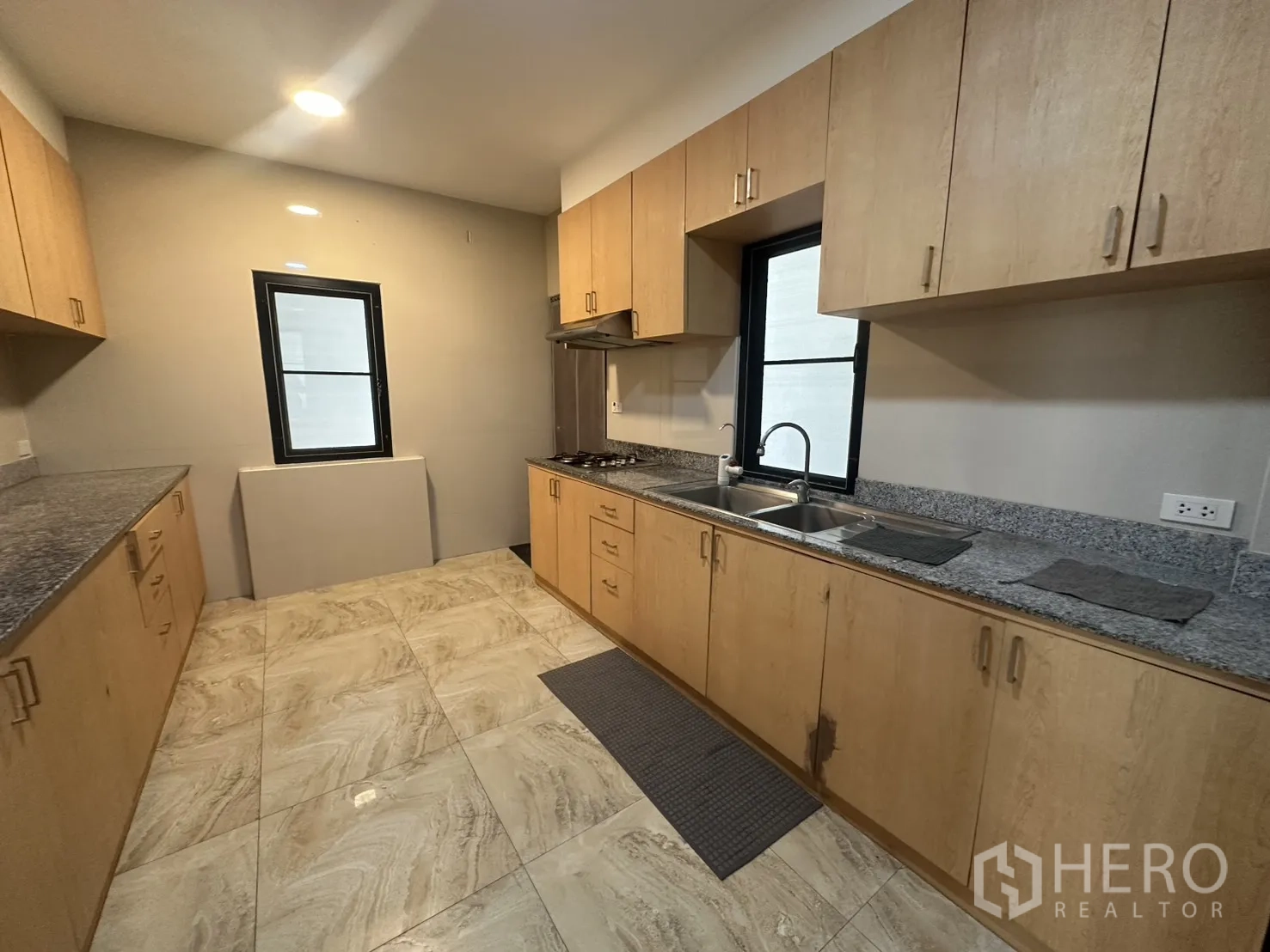 独栋房屋 for rent in Watthana, Bangkok - 走廊式厨房，浅色木柜、花岗岩台面、双水槽与燃气灶