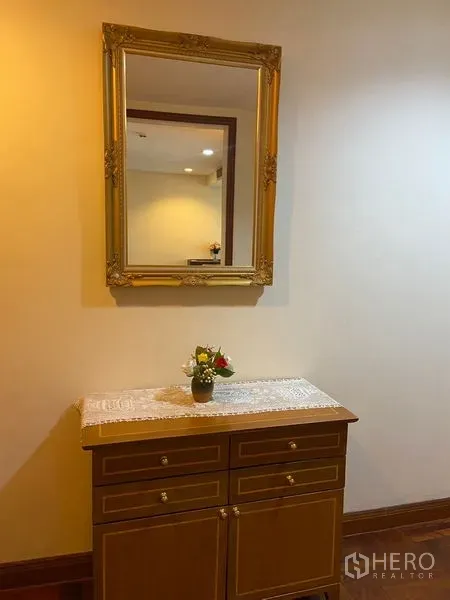 คอนโด ให้เช่าในPathum Wan, Bangkok - ตู้คอนโซลกับกระจกกรอบทองและแจกันดอกไม้ ใต้แสงไฟอบอุ่น