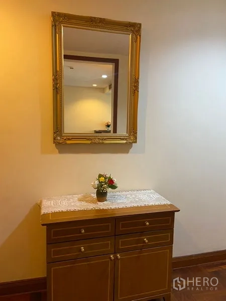 คอนโด ให้เช่าในPathum Wan, Bangkok - ตู้คอนโซลกับกระจกกรอบทองและแจกันดอกไม้ ใต้แสงไฟอบอุ่น